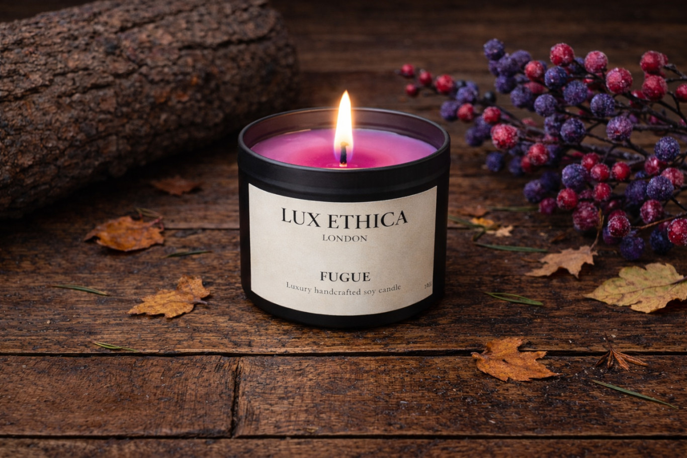 Fugue - Medium A black candle with a pink flame, surrounded by leaves and berries on a wooden surface.